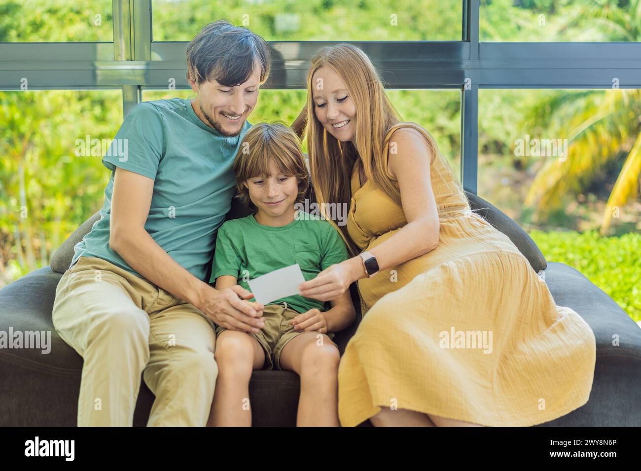 Werdende Mutter und Vater teilen die Freude ihres ungeborenen Babys mit ihrem Sohn und zeigen ihm herzerwärmende Ultraschallfotos von seinem bald ankommenden Kind Stockfoto