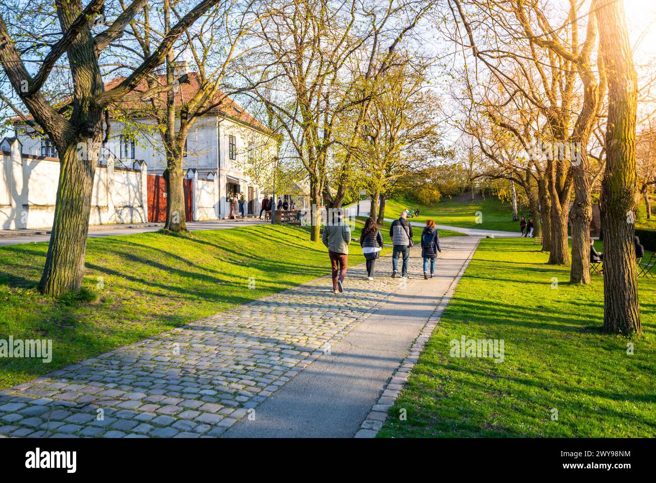 Eine Gruppe von Menschen spaziert gemütlich auf einem Pfad im Vysehrader Park, wo Bäume im frischen Frühlingswetter blühen. Prag, Tschechien Stockfoto