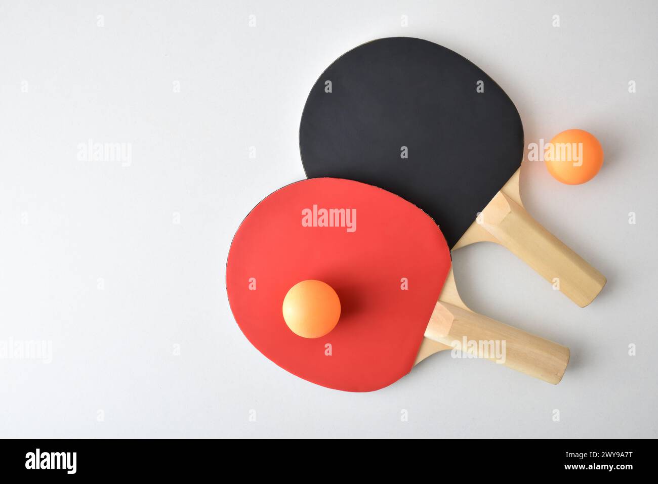 Zwei Tischtennisschläger und zwei orangene Bälle isoliert auf weißem Tisch. Draufsicht. Stockfoto