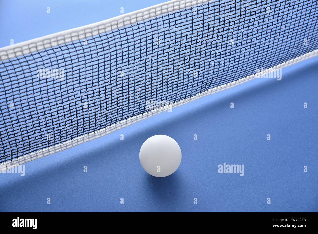Pingpong Hintergrund mit weißem Ball neben dem Netz auf einem blauen Spieltisch. Erhöhte Aussicht. Stockfoto