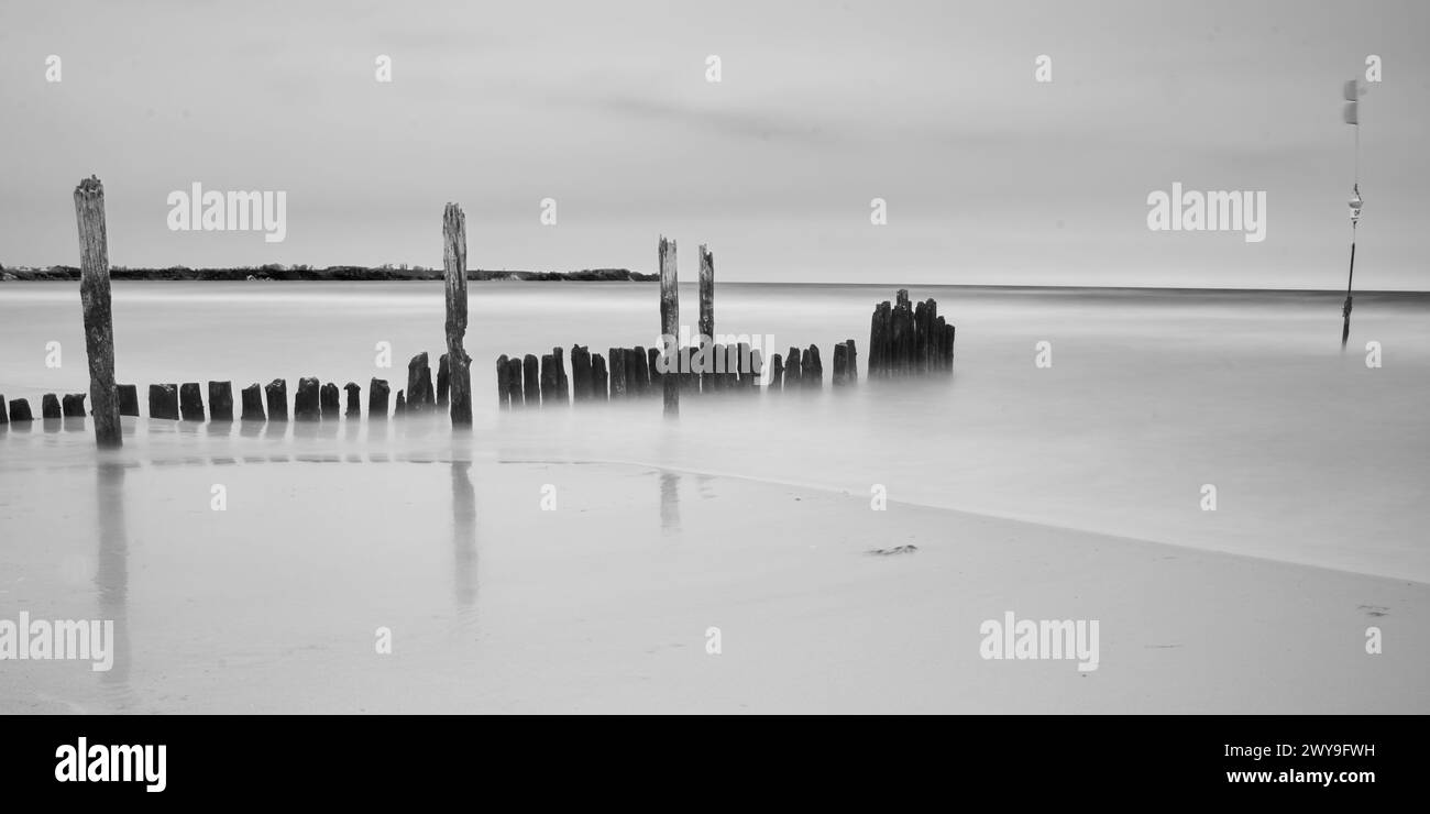 Ein grauer Schuss von Überresten eines Holzpiers am Meer. Stockfoto