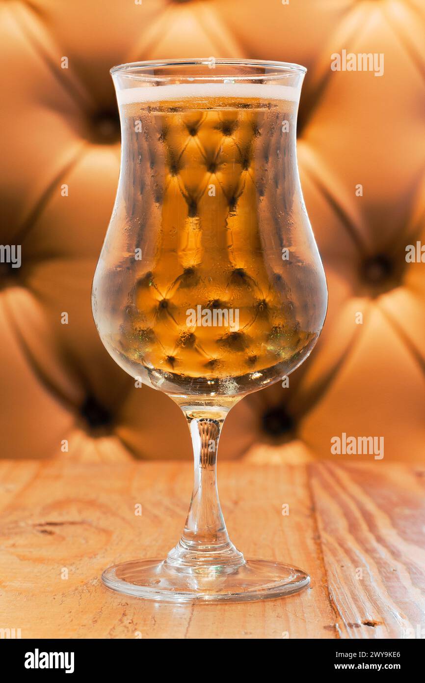 Ein Glas Champagner vor einer getufteten beigefarbenen Kabine Stockfoto