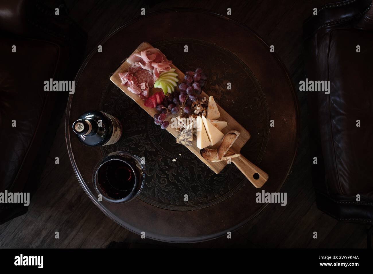 Blick von oben auf ein Pub-Brett auf einem runden Tisch mit einer Flasche Wein Stockfoto