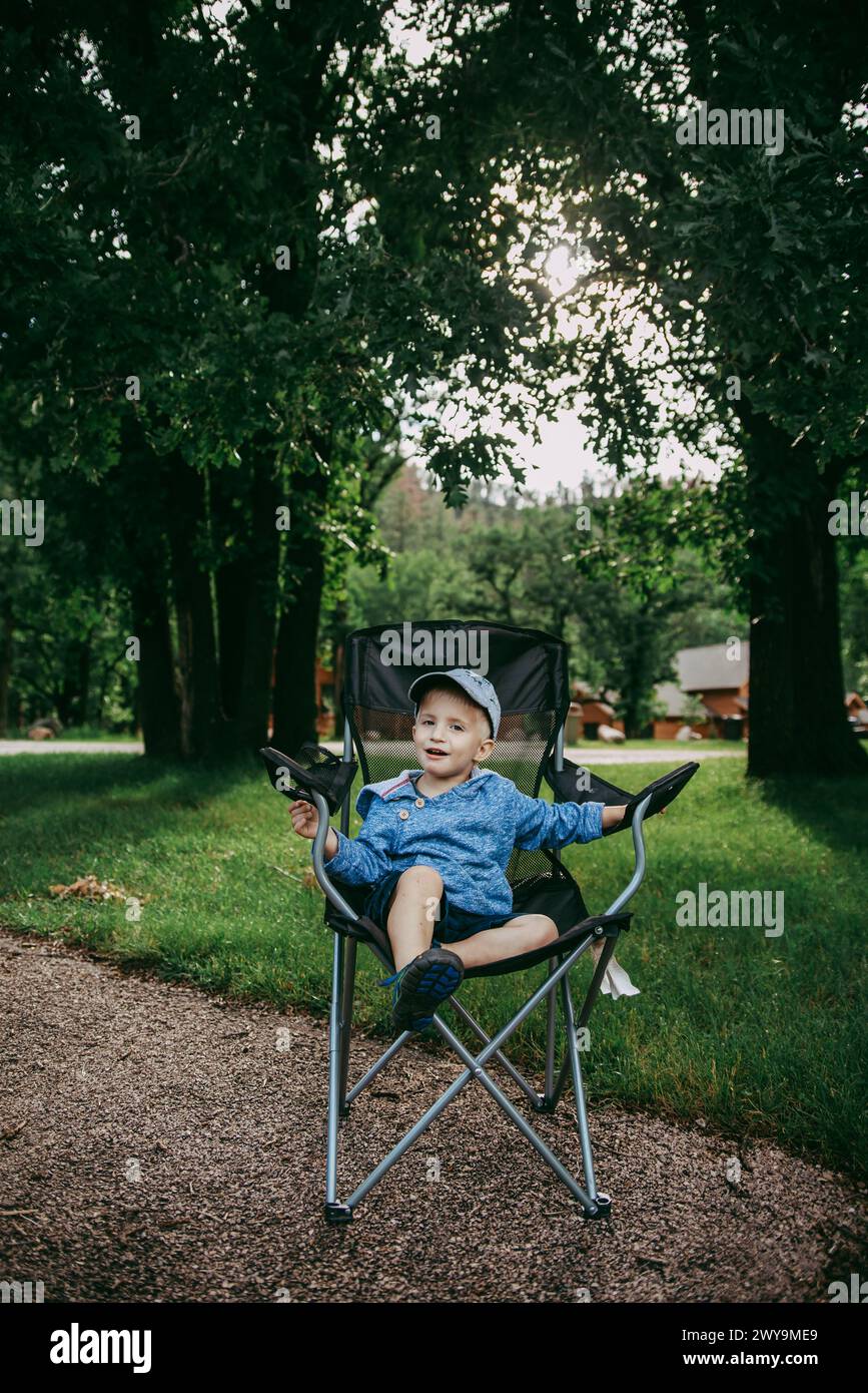 Lächelndes Kleinkind, das im Sommer auf dem Campingplatz sitzt Stockfoto