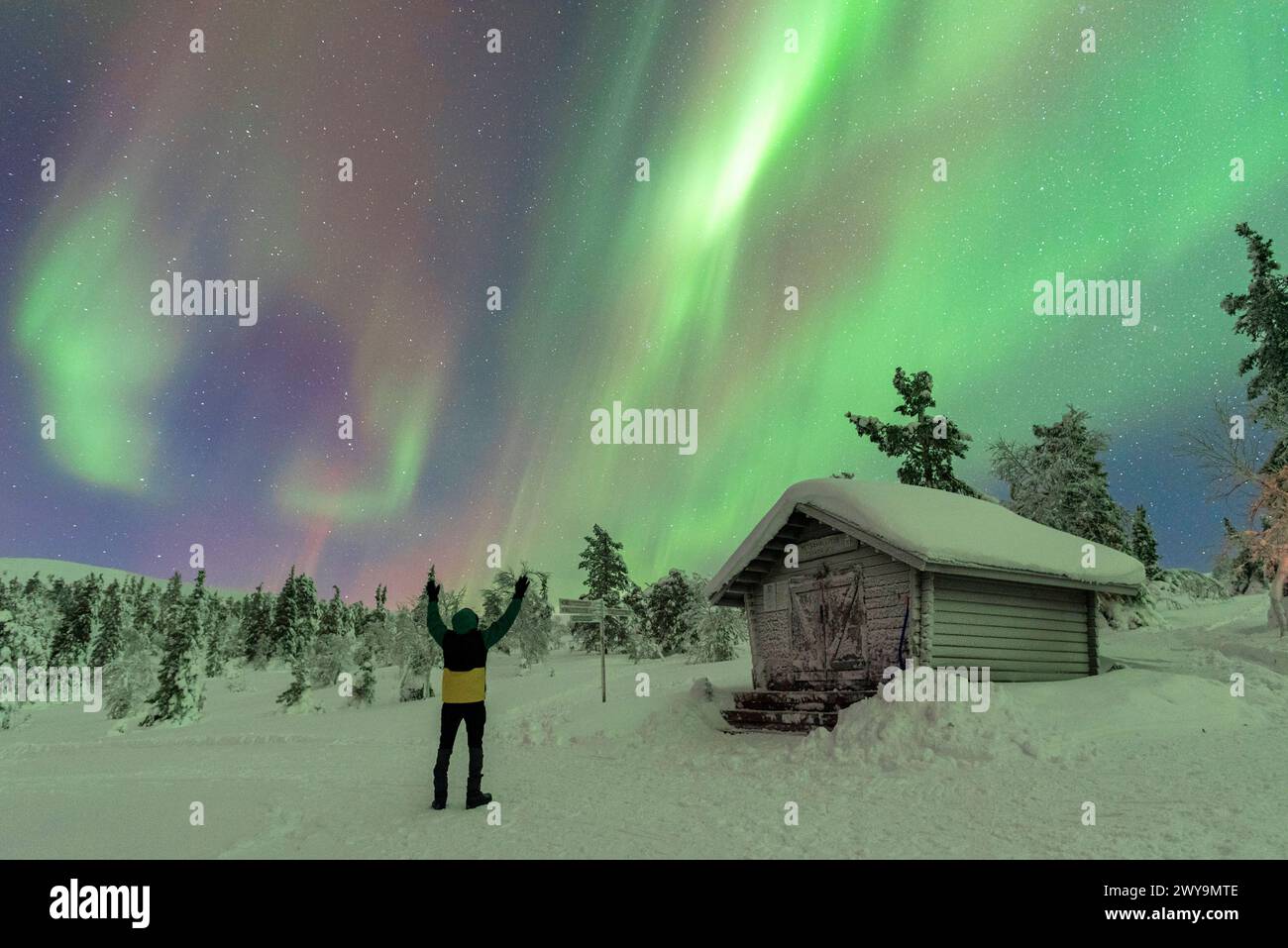 Glückliche Touristen winken bei den Nordlichtern Aurora Borealis, tanzen am Nachthimmel über dem Polarkreis, Akaslompolo, Kolari Gemeinde, Finlan Stockfoto