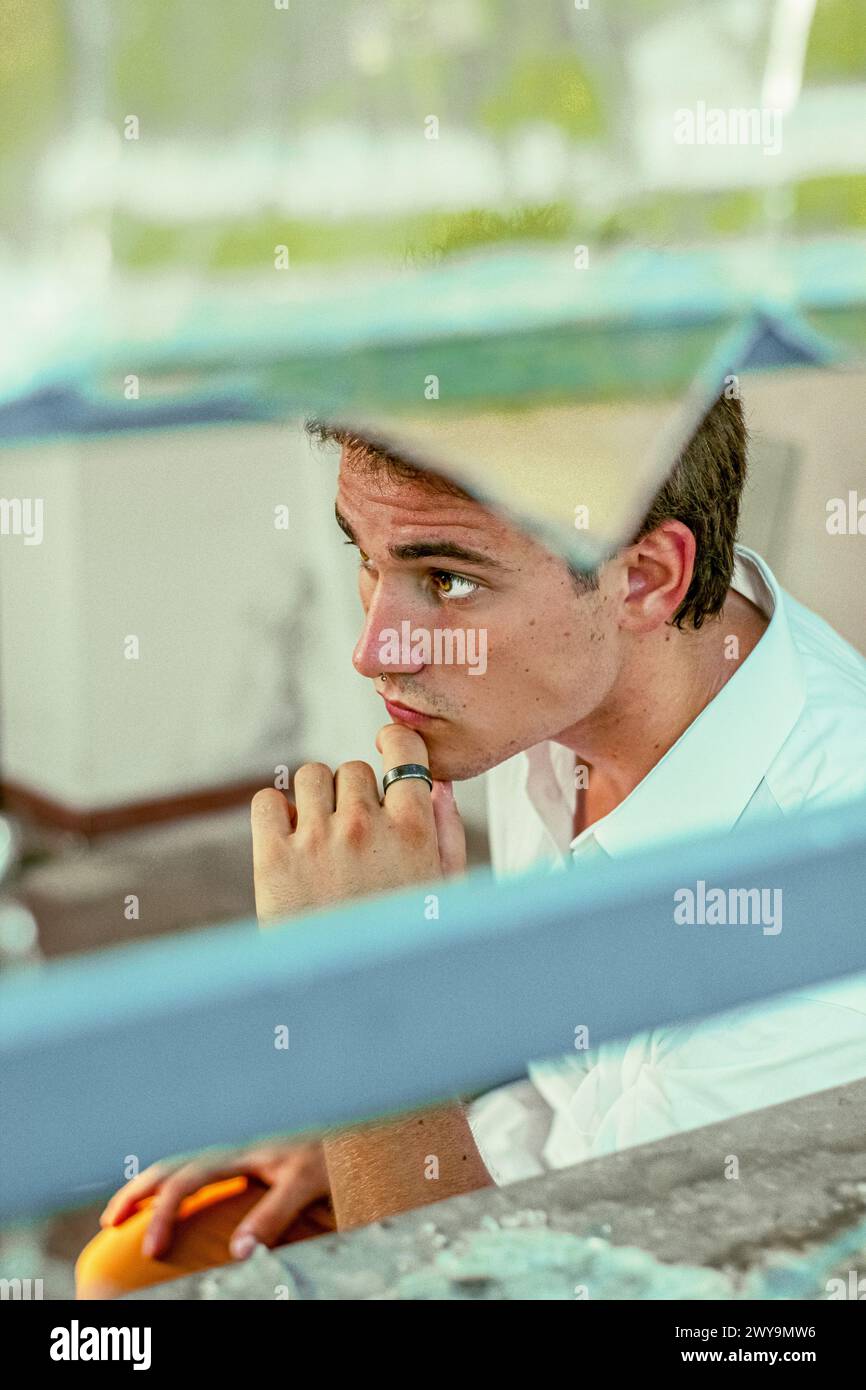 Junger, gutaussehender Mann, der durch Glasbruch aus der Kamera schaut Stockfoto