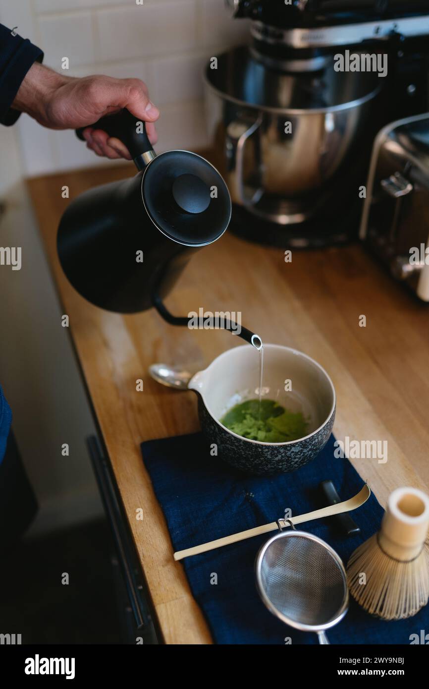 Wasserkocher gießen Sie kochendes Wasser in Matcha-Teepulver Stockfoto