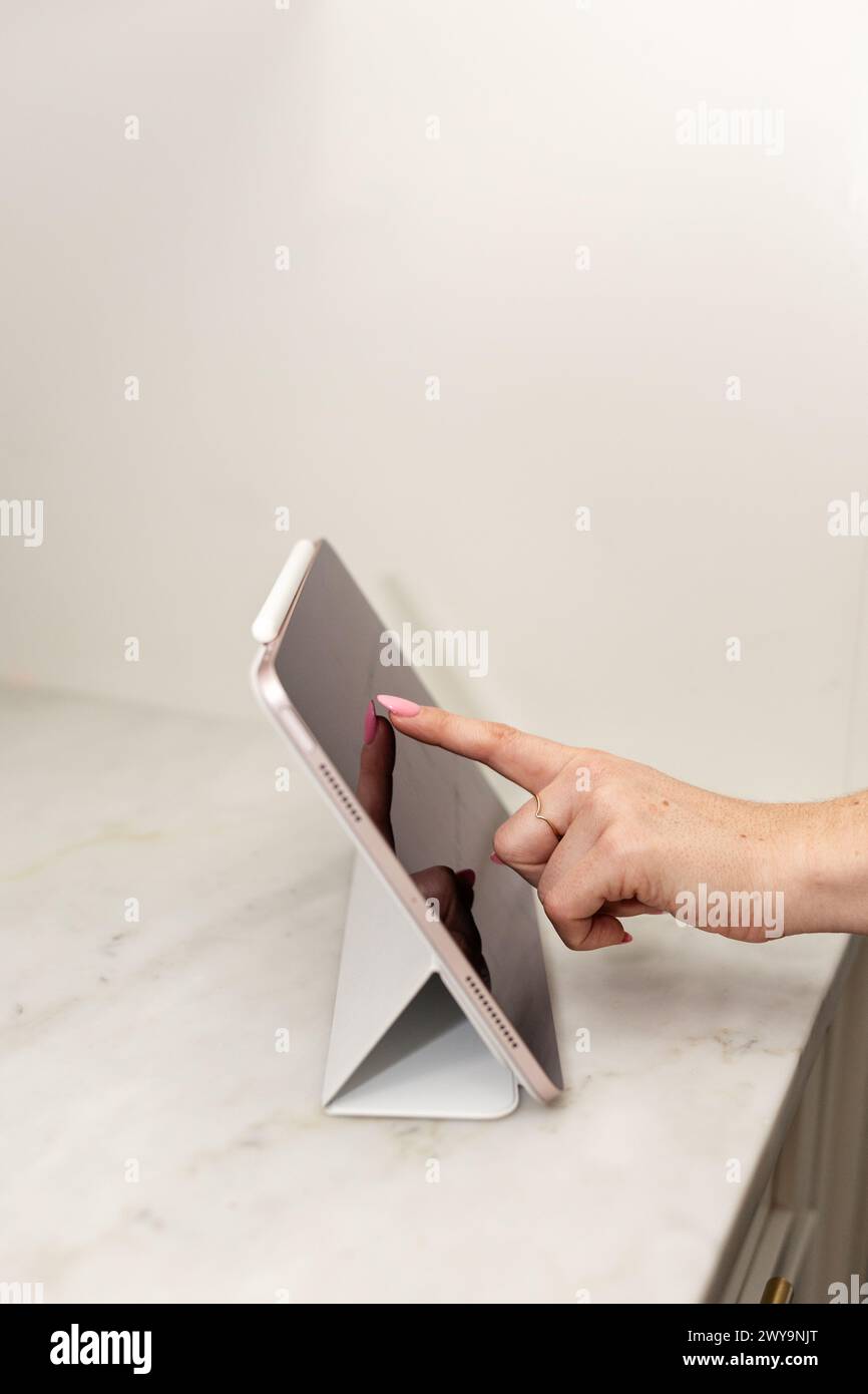 Berühren Sie eine Tablette mit dem Finger auf einer Marmoroberfläche Stockfoto
