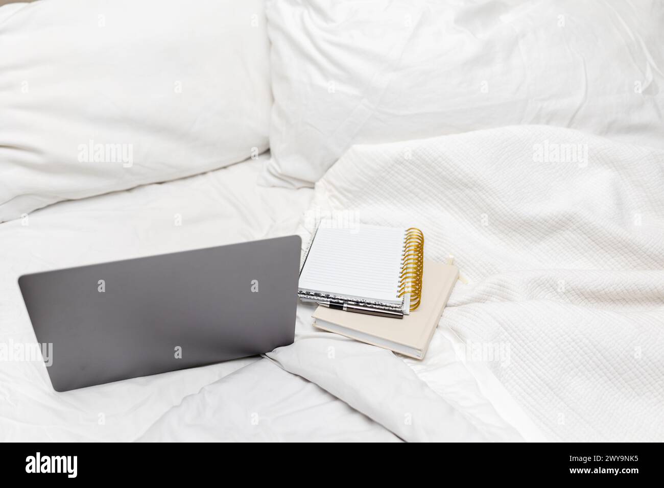 Arbeiten Sie mit Laptop auf einem gemütlichen Bett Stockfoto