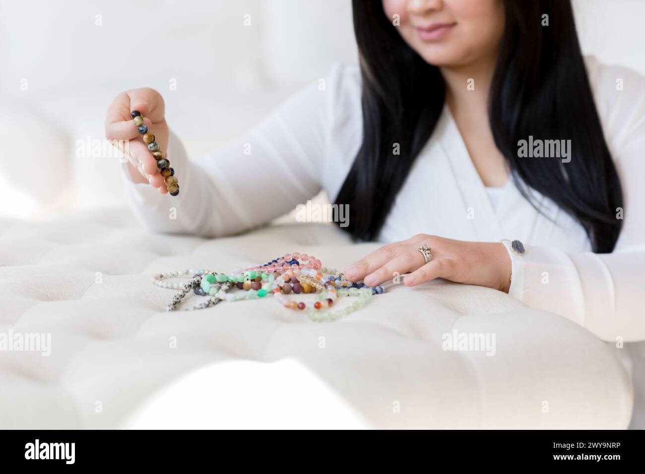 Asiatische Frau sortiert Perlenarmbänder für spirituelle Heilung Stockfoto