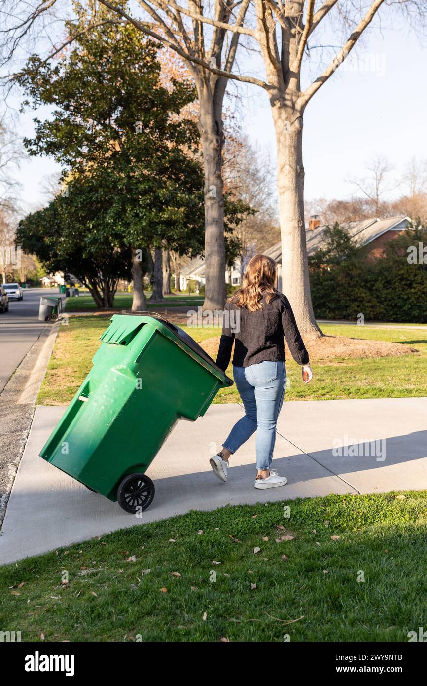 Rückansicht einer Frau mit grünem Recyclingbehälter Stockfoto