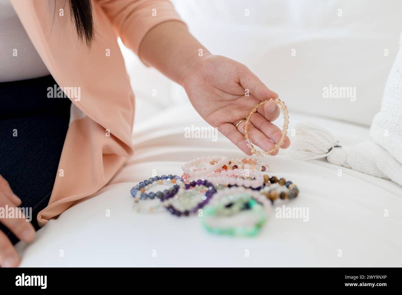 Asiatische Frau sortiert Perlenarmbänder für spirituelle Heilung Stockfoto