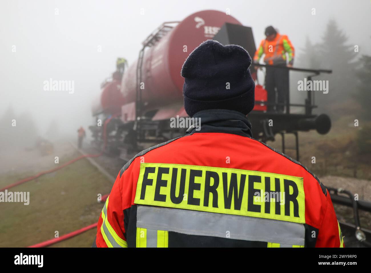 Schierke, Deutschland. April 2024. Zwei Kesselwagen der Harzer Schmalspurbahn (HSB) stehen auf dem Goethe-Aufstieg im Harz. Ein Löschwasserbehälter mit einer Kapazität von 100.000 Litern Löschwasser für den Brandschutz wird von der Feuerwehr Wernigerode in einer Höhe von 950 m gefüllt Quelle: Peter Gercke/dpa-Zentralbild/dpa/Alamy Live News Stockfoto