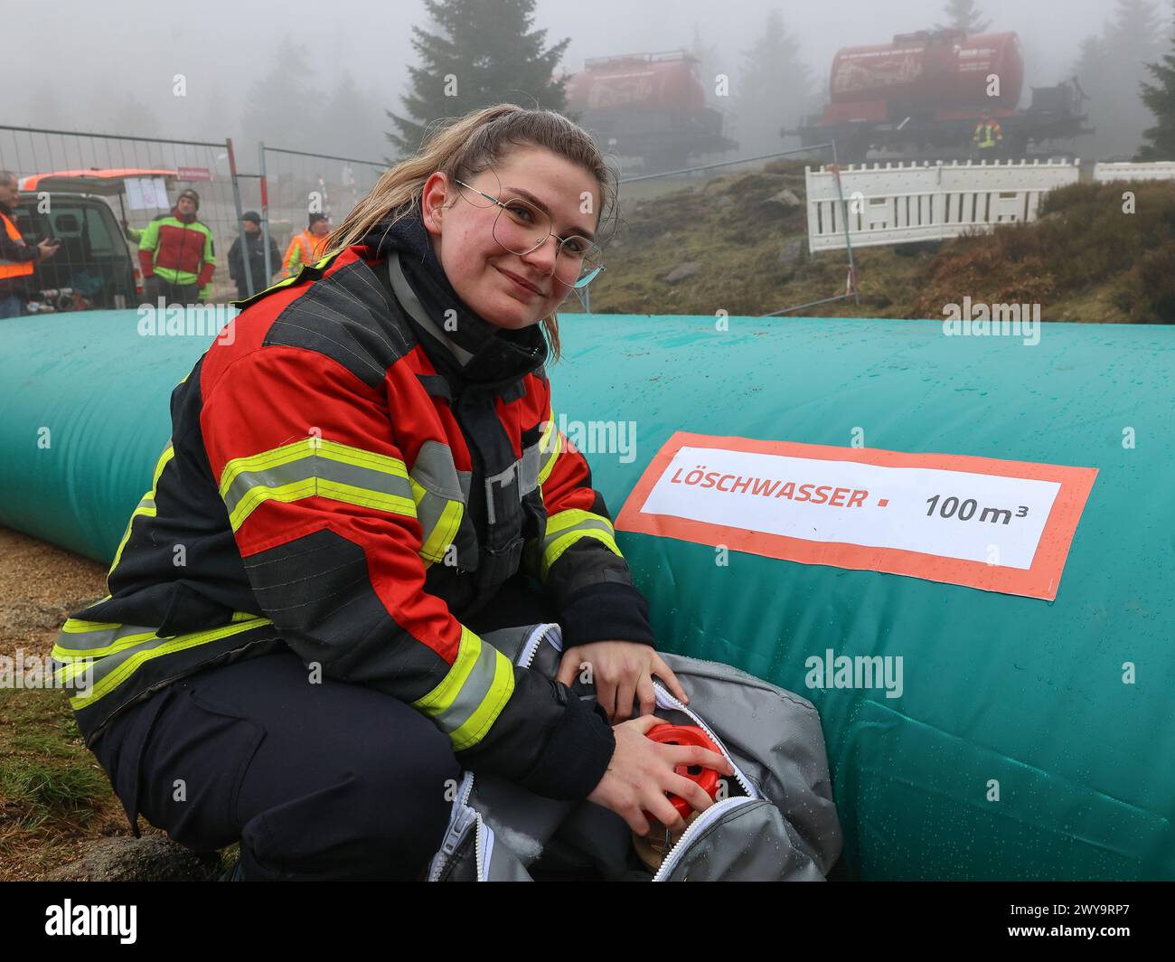 Schierke, Deutschland. April 2024. Emily Rettmer von der Feuerwehr Wernigerode überprüft ein Wasserreservoir am Goethe-Steig im Harz. Ein Löschwasserbehälter mit einer Kapazität von 100.000 Litern Löschwasser für den Brandschutz wird von der Feuerwehr Wernigerode in einer Höhe von 950 m gefüllt Quelle: Peter Gercke/dpa-Zentralbild/dpa/Alamy Live News Stockfoto