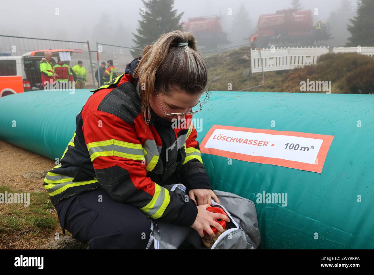 Schierke, Deutschland. April 2024. Emily Rettmer von der Feuerwehr Wernigerode überprüft ein Wasserreservoir am Goethe-Steig im Harz. Ein Löschwasserbehälter mit einer Kapazität von 100.000 Litern Löschwasser für den Brandschutz wird von der Feuerwehr Wernigerode in einer Höhe von 950 m gefüllt Quelle: Peter Gercke/dpa-Zentralbild/dpa/Alamy Live News Stockfoto