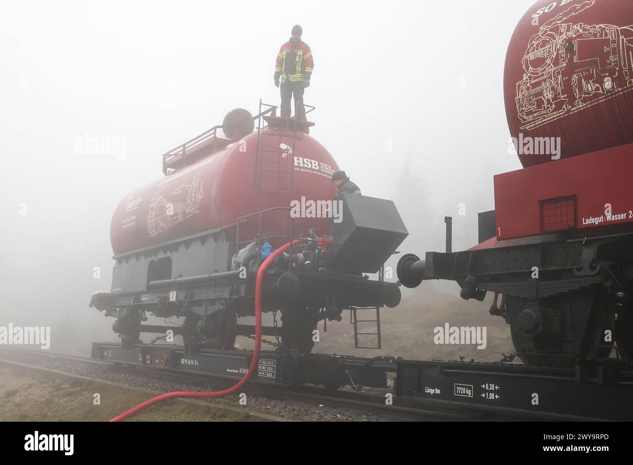 Schierke, Deutschland. April 2024. Zwei Kesselwagen der Harzer Schmalspurbahn (HSB) stehen auf dem Goethe-Aufstieg im Harz. Ein Löschwasserbehälter mit einer Kapazität von 100.000 Litern Löschwasser für den Brandschutz wird von der Feuerwehr Wernigerode in einer Höhe von 950 m gefüllt Quelle: Peter Gercke/dpa-Zentralbild/dpa/Alamy Live News Stockfoto