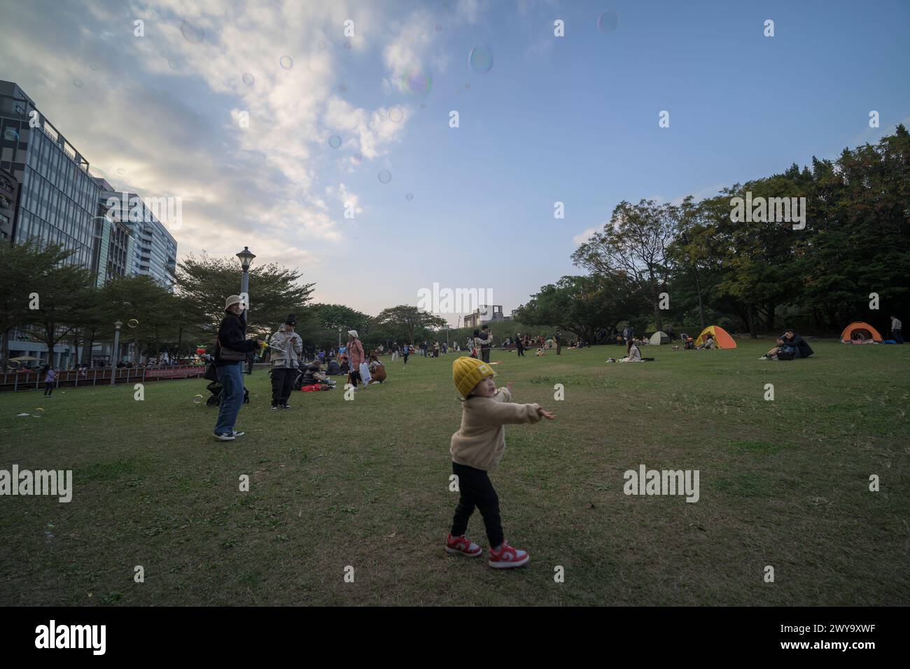 Eine fröhliche Szene, in der Kinder mit Seifenblasen spielen und Familien einen sonnigen Tag im Huashan Park genießen Stockfoto
