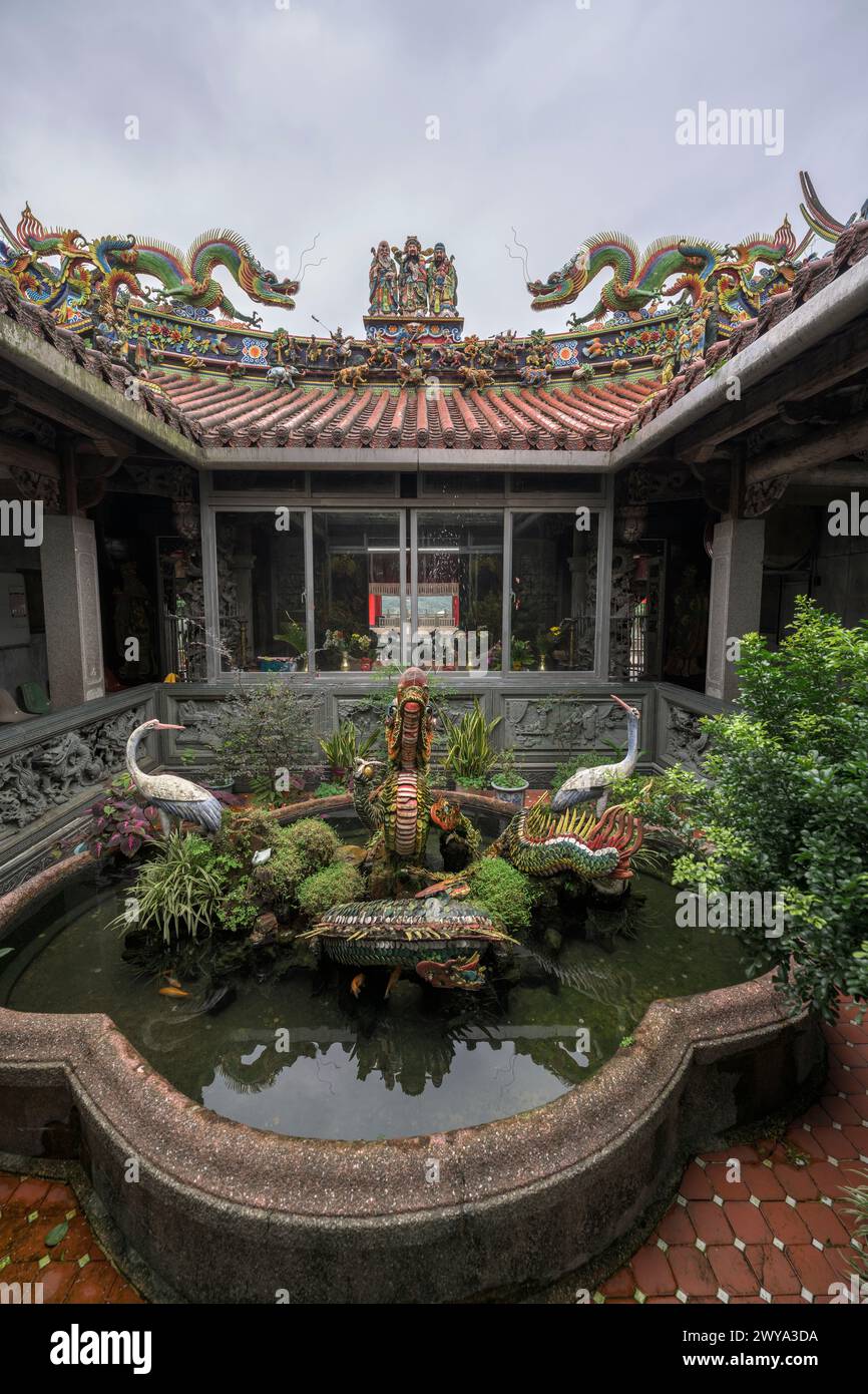 Ein friedlicher, ruhiger Innenhof im Chuen Ji Hall Tempelgelände mit Fischteich und Skulpturen inmitten von Grün Stockfoto