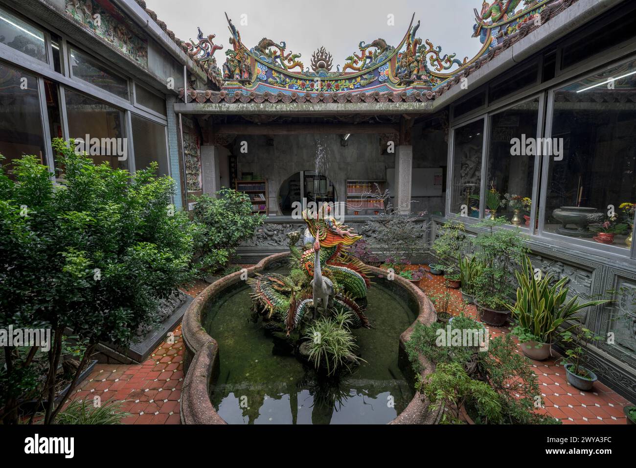 Ein friedlicher, ruhiger Innenhof im Chuen Ji Hall Tempelgelände mit Fischteich und Skulpturen inmitten von Grün Stockfoto