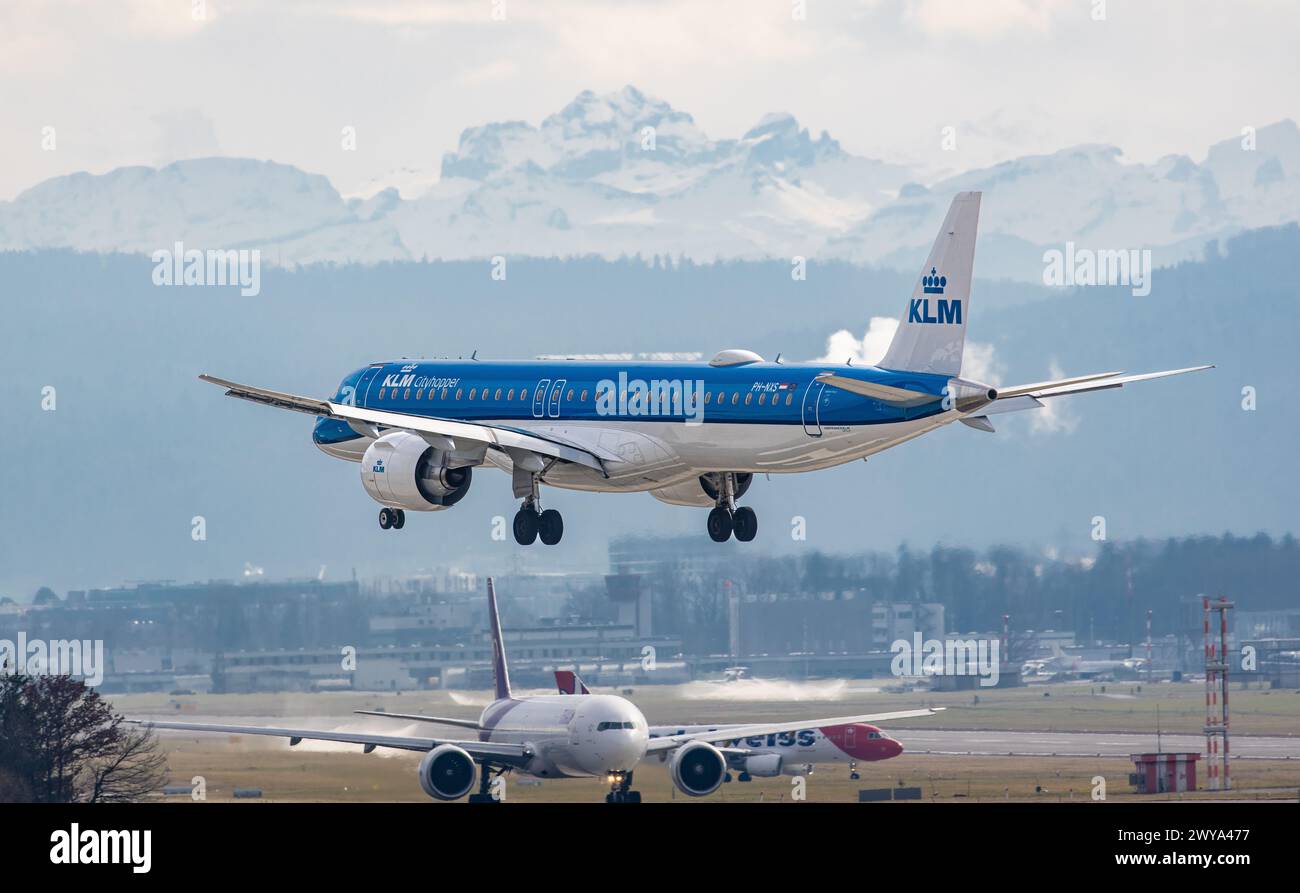 Ein Embraer 195-E2 von KLM Cityhopper befindet sich im Endlandeanflug auf den Flughafen Zürich. Registrierung PH-NXS. Dahinter weitere Flugzeuge, welch Stockfoto