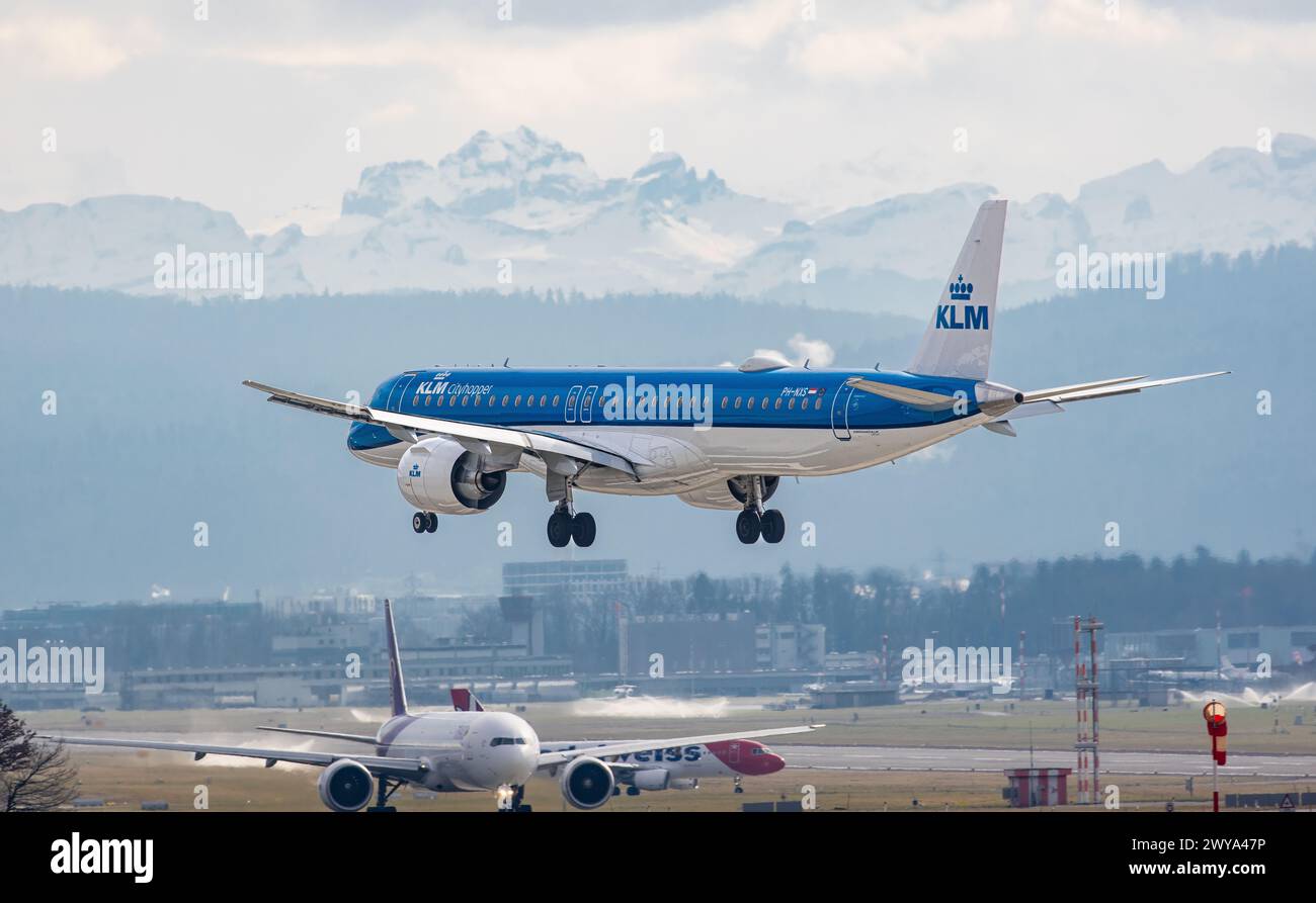 Ein Embraer 195-E2 von KLM Cityhopper befindet sich im Endlandeanflug auf den Flughafen Zürich. Registrierung PH-NXS. Dahinter weitere Flugzeuge, welch Stockfoto