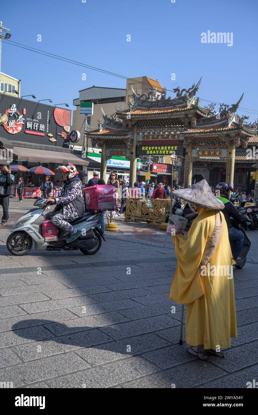 Eine lebhafte Szene am Eingang des Mazu-Tempels mit einer Straße voller Händler, Besucher und einem bettelnden Pilger Stockfoto