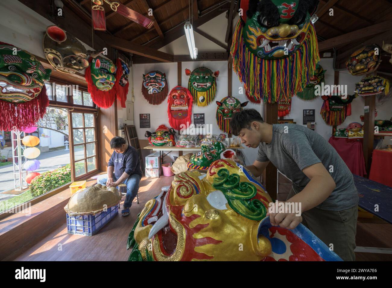 In einem traditionellen Kunsthandwerksstudio in Lukang arbeiten Handwerker an lebhaften zeremoniellen Masken Stockfoto