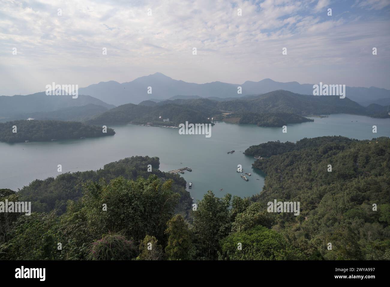 Ein ruhiger Blick aus der Luft auf einen riesigen See, umgeben von üppigen grünen Hügeln und bewölktem Himmel Stockfoto