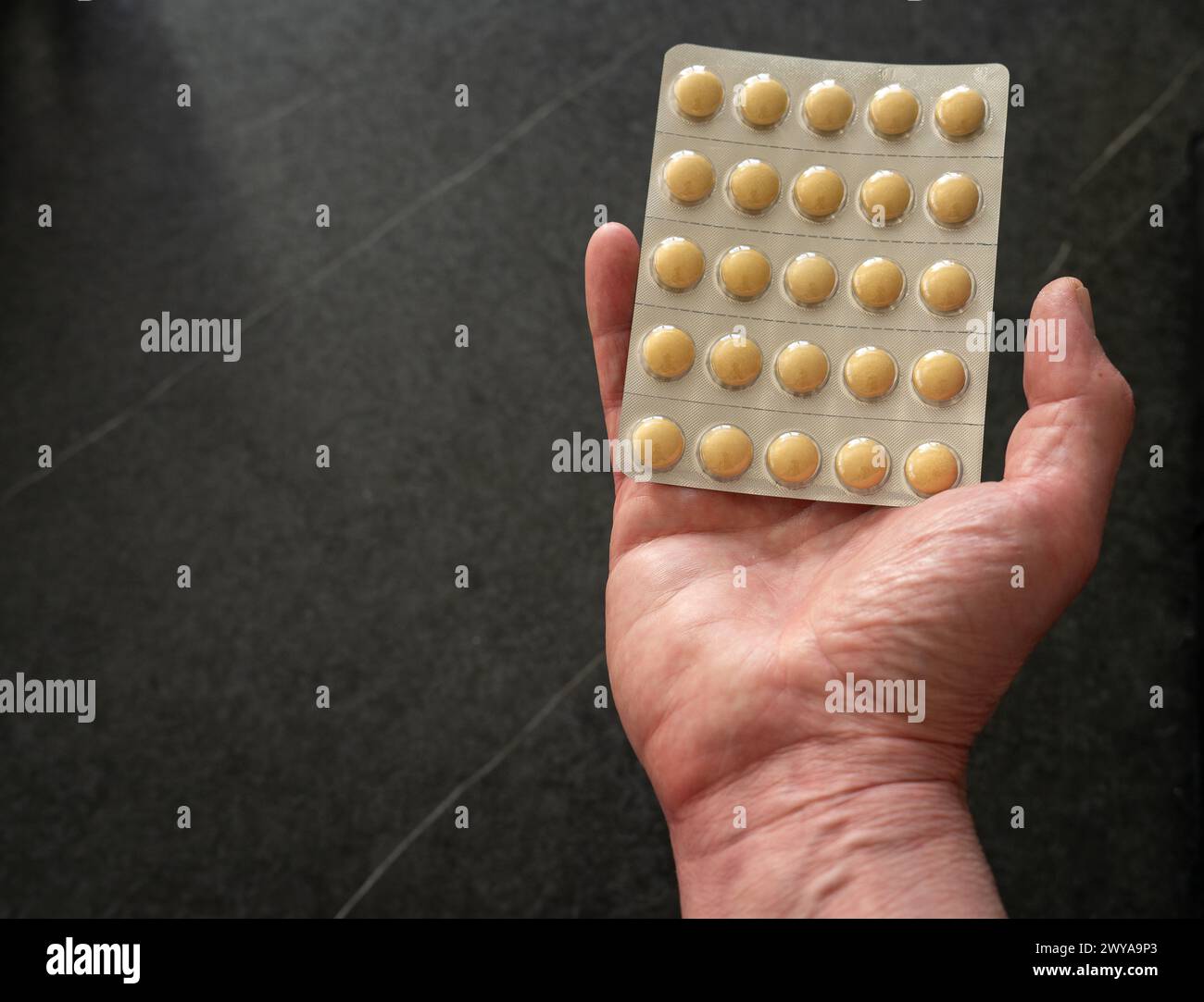 Hand hält eine Pillen-Blisterpackung und präsentiert sie. Schwarzer Hintergrund, Leerraum. Stockfoto
