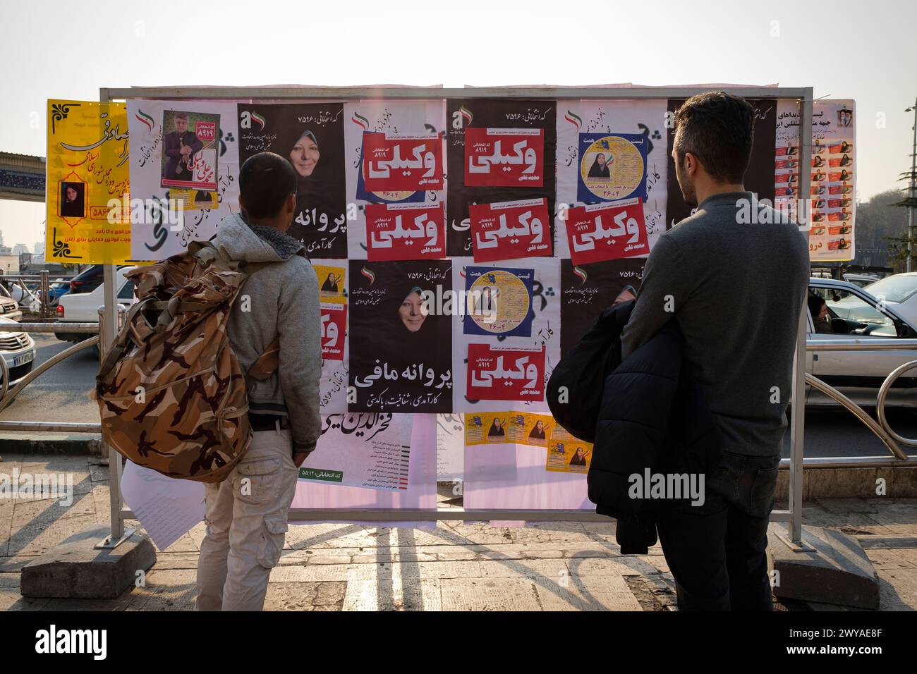 Parlamentswahlen im Iran und zwei Iraner, die die Plakate der Kandidaten für die Kundgebung beobachten. Stockfoto