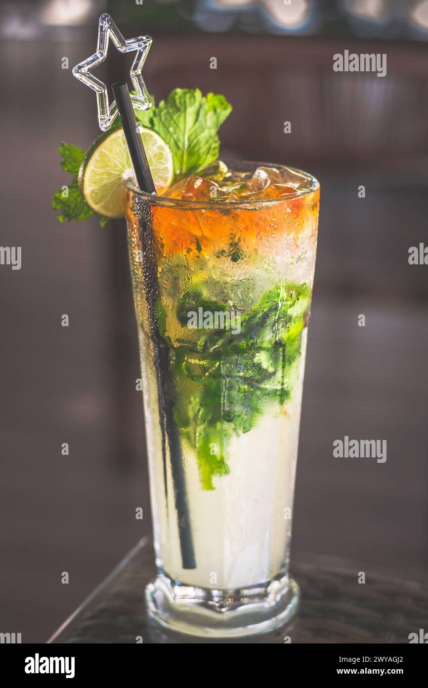 Ein Mojito in einem hohen Glas mit Strohhalm serviert und mit einer Limettenscheibe belegt Stockfoto