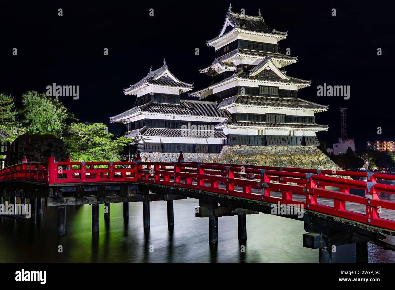 Japanisches Matsumoto Castle und rote Brücke spiegeln sich nachts in seinem Graben Stockfoto