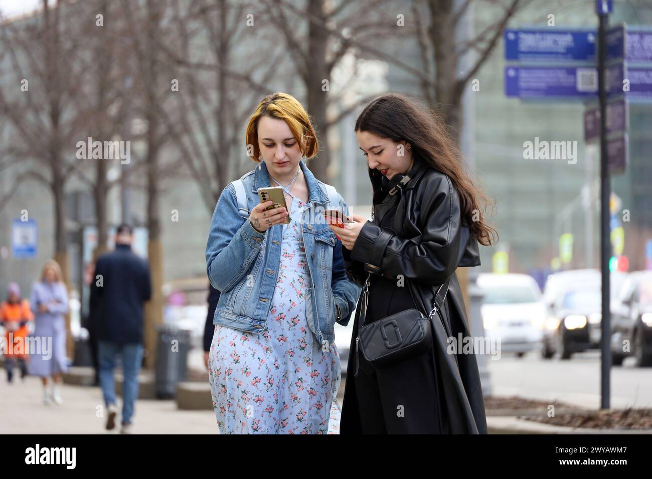 Zwei junge Frauen mit Smartphones stehen auf der Straße der Stadt Stockfoto
