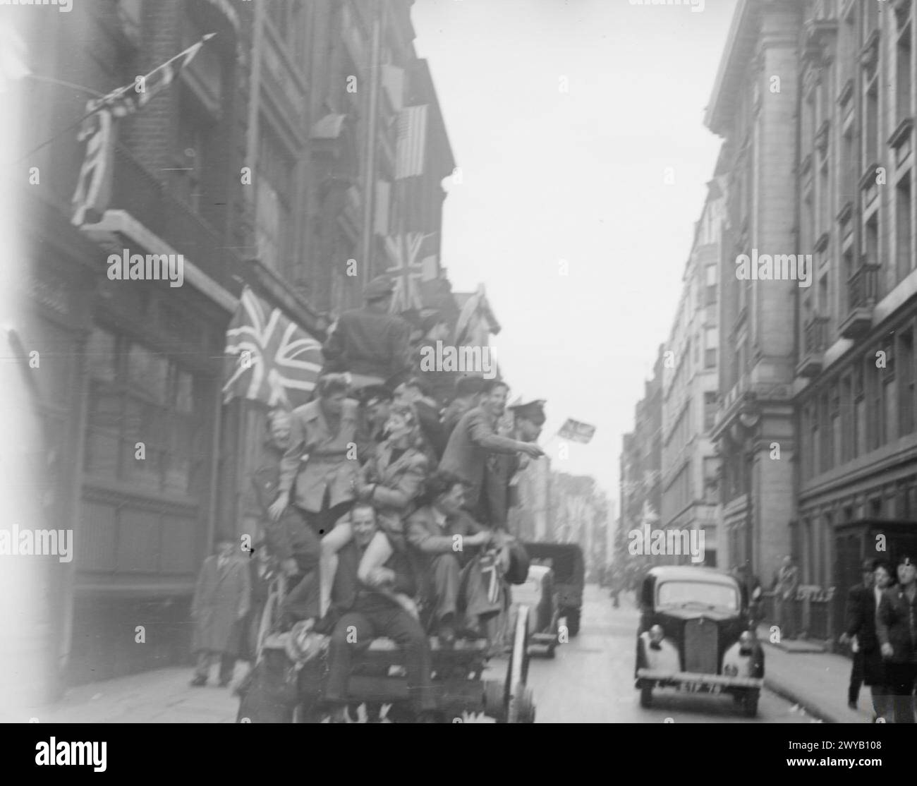 Die Menschen feiern den VE Day am 8. Mai 1945 in Richmond, Surrey, mit Pferdekutschen, Menschenmassen und Fahnen vor dem Buckingham Palace. Stockfoto