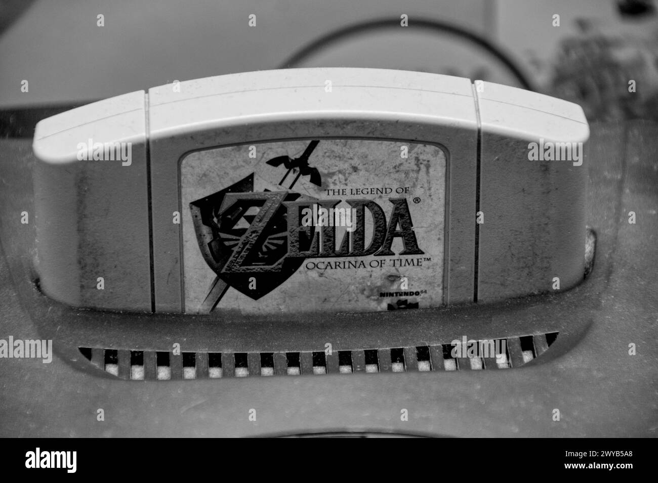 Schwarz-weiß-Foto eines alten staubigen Nintendo 64 mit einem Legend of Zelda-Spiel auf der Konsole Stockfoto