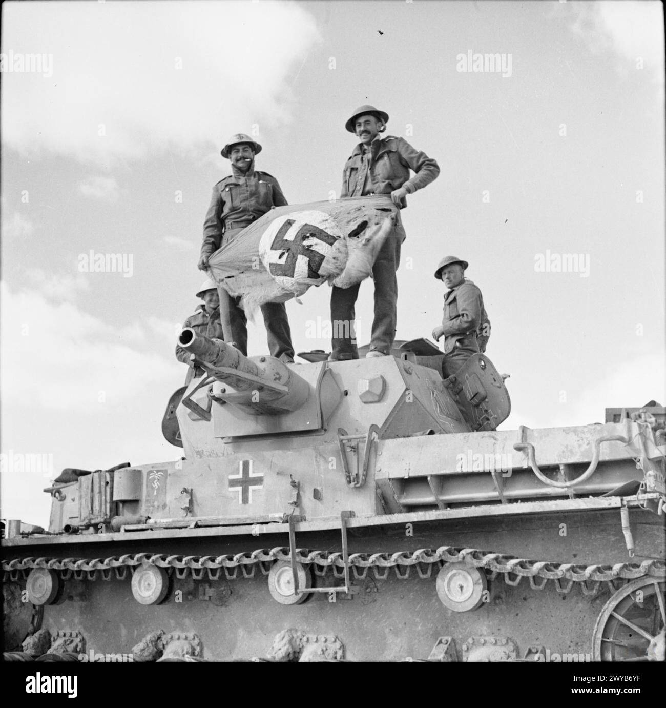 Am 26. November 1941 hielten zwei britische Armeesoldaten in Nordafrika eine Nazi-Hakenkreuzfahne, die von einem deutschen PzKpfw IV Panzer in der Westwüste geborgen wurde. Fotografisches negativ, britische Armee. Stockfoto