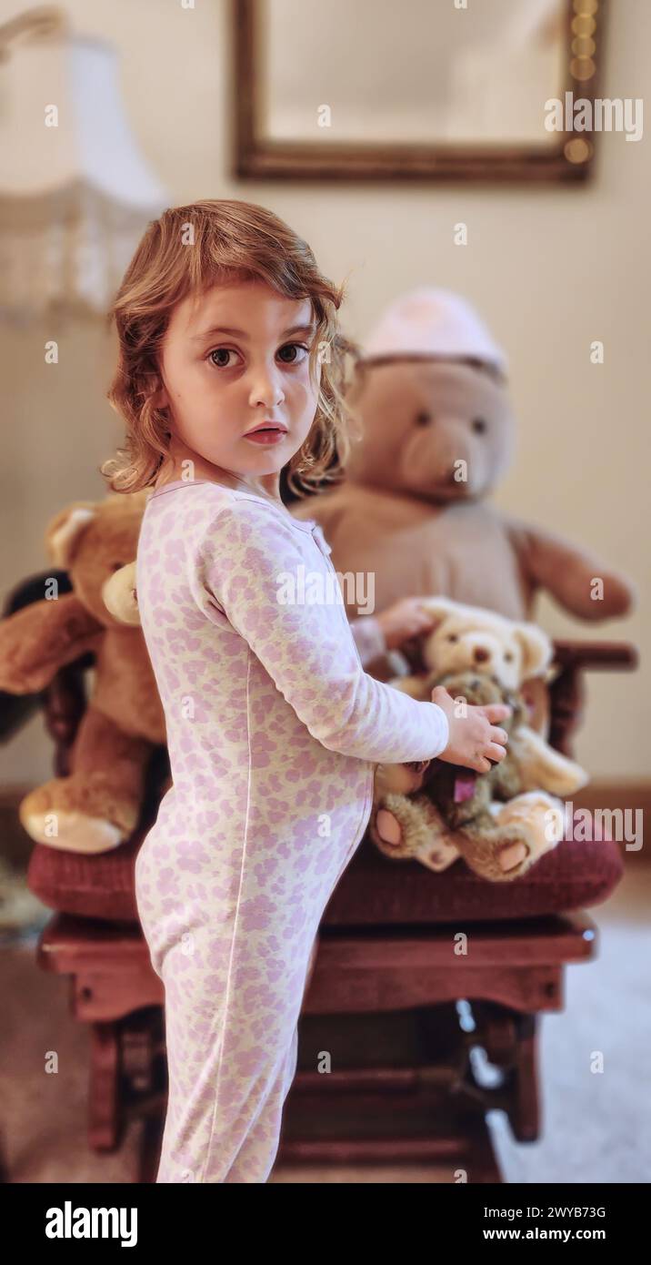 Ein kleines Mädchen, das in die Kamera schaut, während er einen Teddybären hält Stockfoto