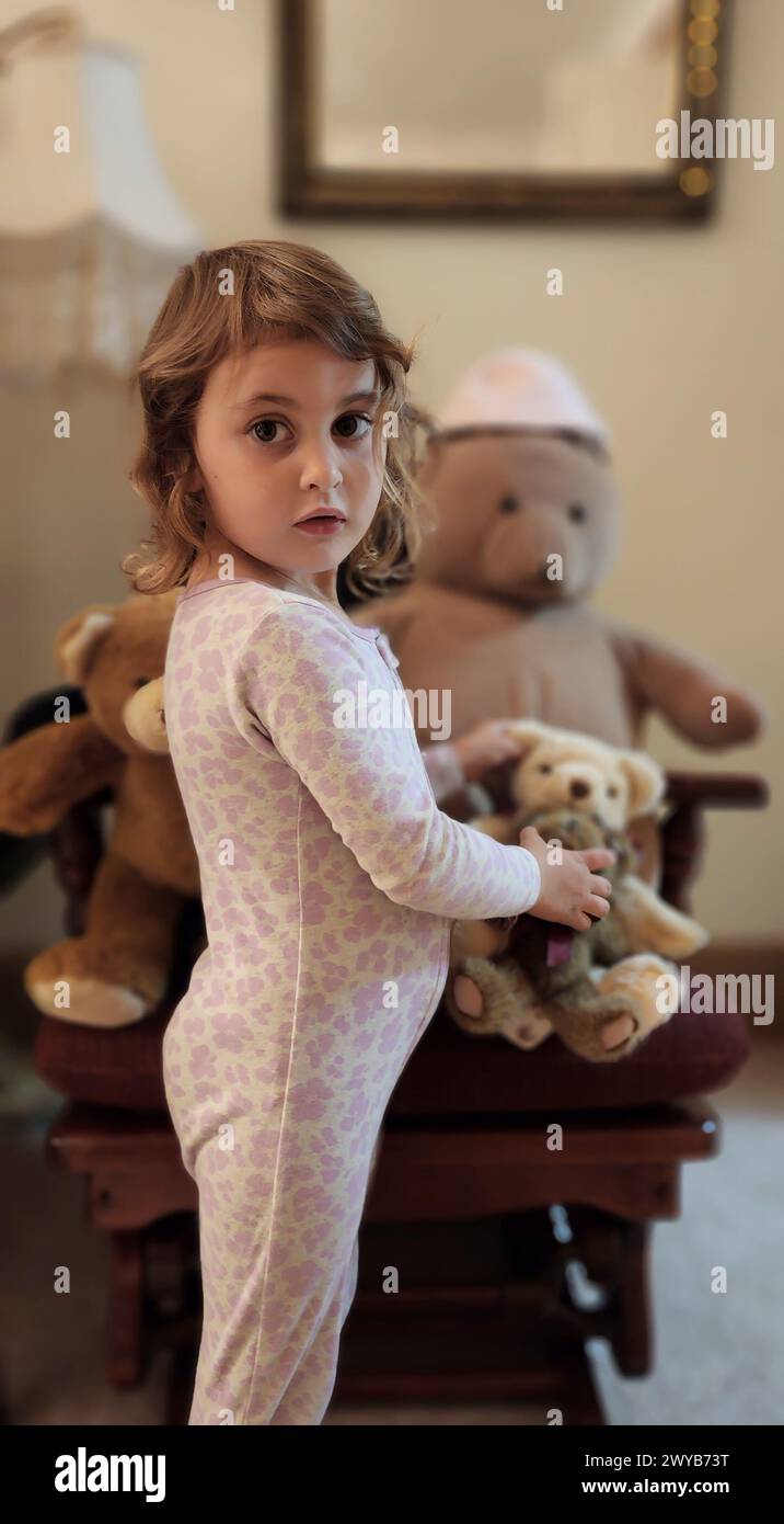 Ein kleines Mädchen, das in die Kamera schaut, während er einen Teddybären hält Stockfoto