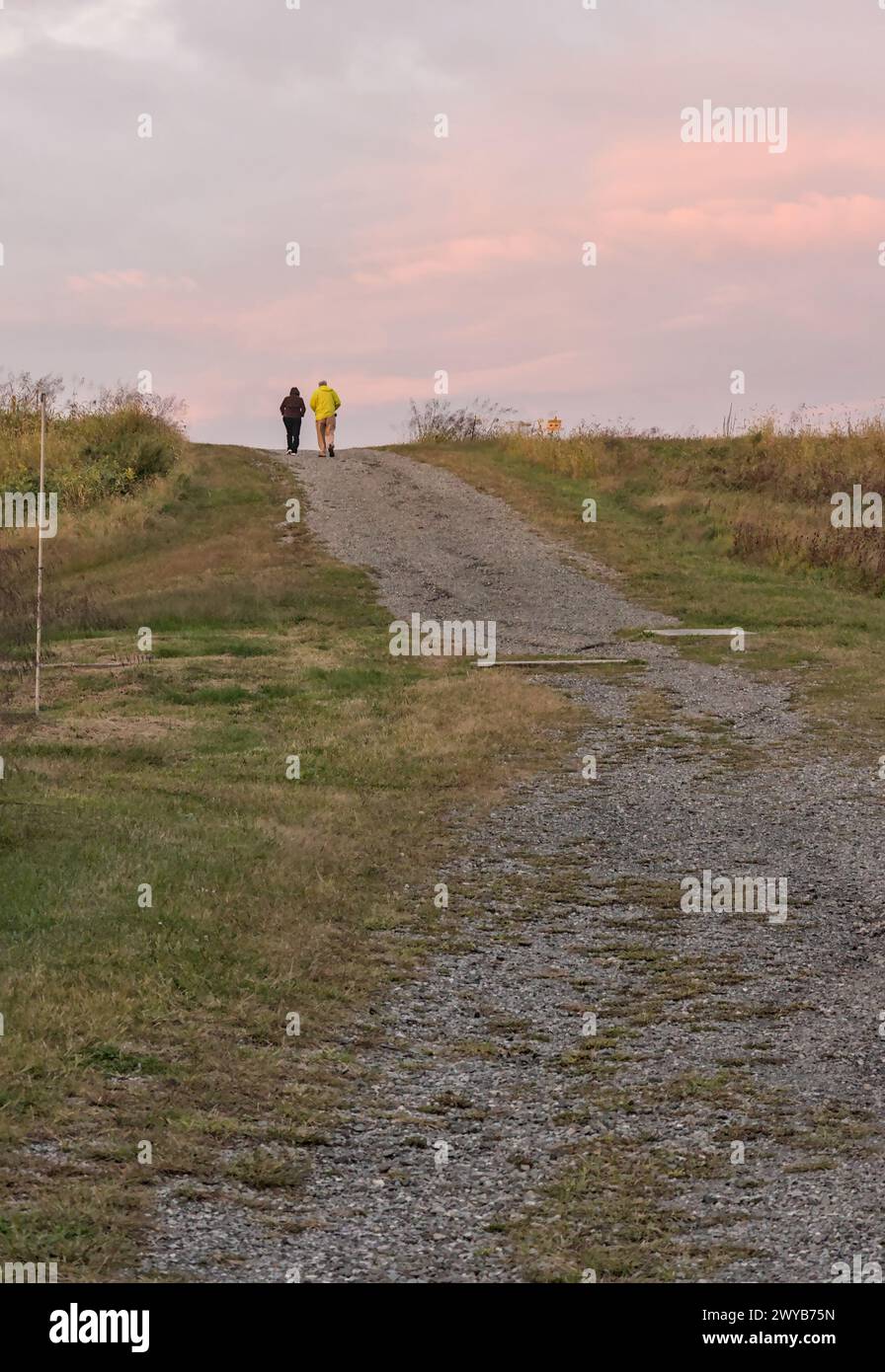 Älteres Ehepaar, das in der Abenddämmerung auf einem Schotterweg in einem State Park auf einem Hügel spaziert (ältere Menschen, nicht erkennbare Menschen, Natur, Wandern, Spaziergang, Erholung) Foto fr Stockfoto