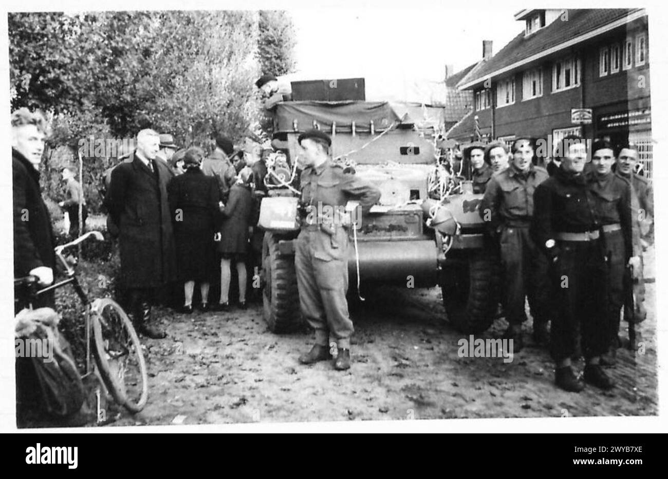 In Dirschot ist ein halbgleisiges Aufklärungsfahrzeug dekoriert und fast von Zivilisten umgeben, während drei deutsche Gefangene von britischen Truppen verhört werden. Stockfoto