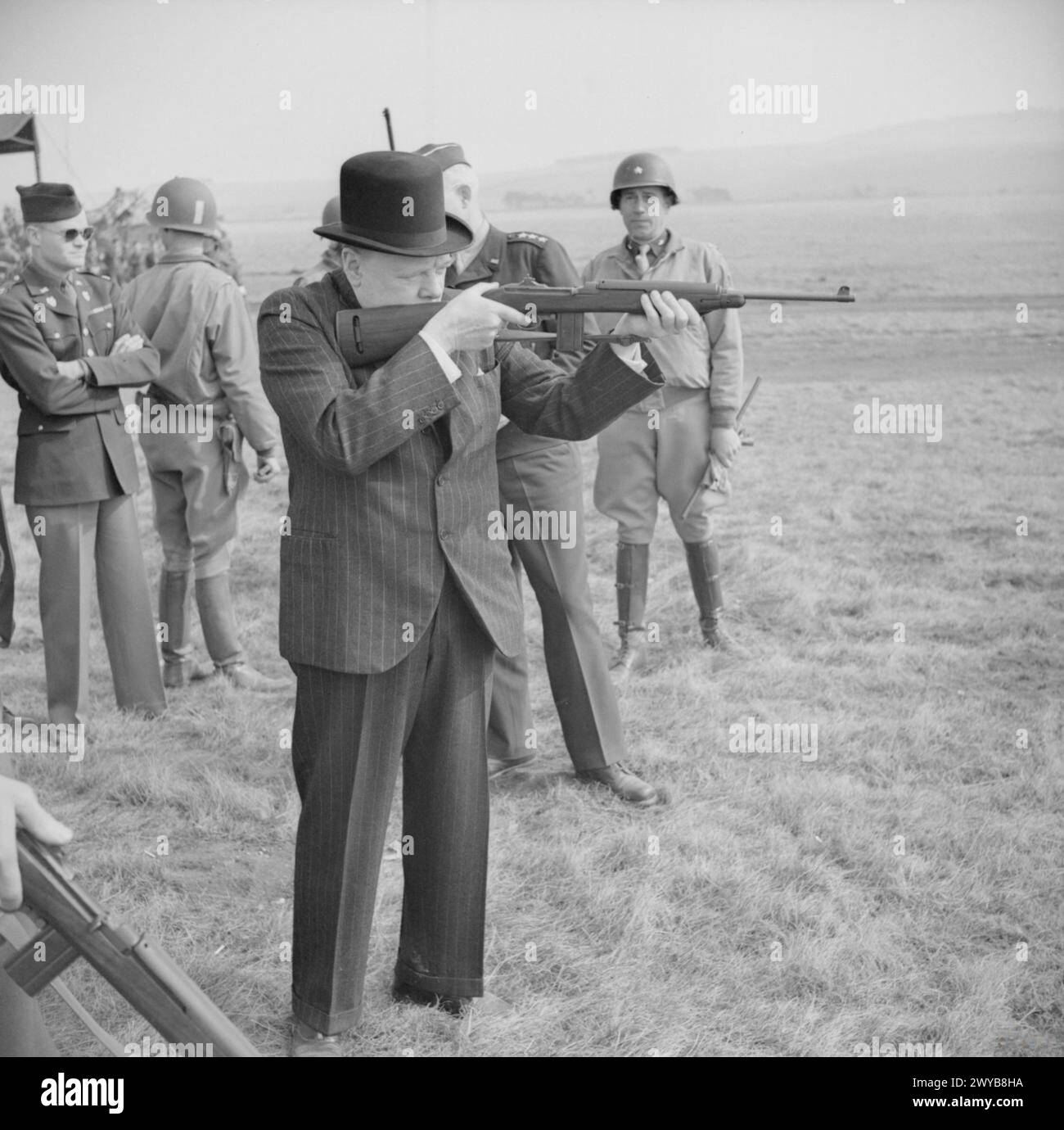 Winston Churchill feuert einen amerikanischen .30-Karabiner während eines Besuchs der 2. Panzerdivision der USA auf der Salisbury Plain, Großbritannien, am 23. März 1944, um die militärische Zusammenarbeit zu veranschaulichen. Stockfoto
