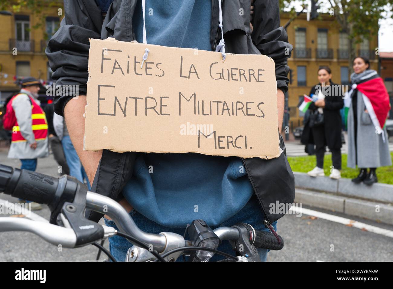 Ein Radfahrer, der mit einem Plakat demonstriert, macht Krieg zwischen den Militärs, danke, mit einem Demonstranten auf beiden Seiten mit einer CGT-Flagge. Stockfoto