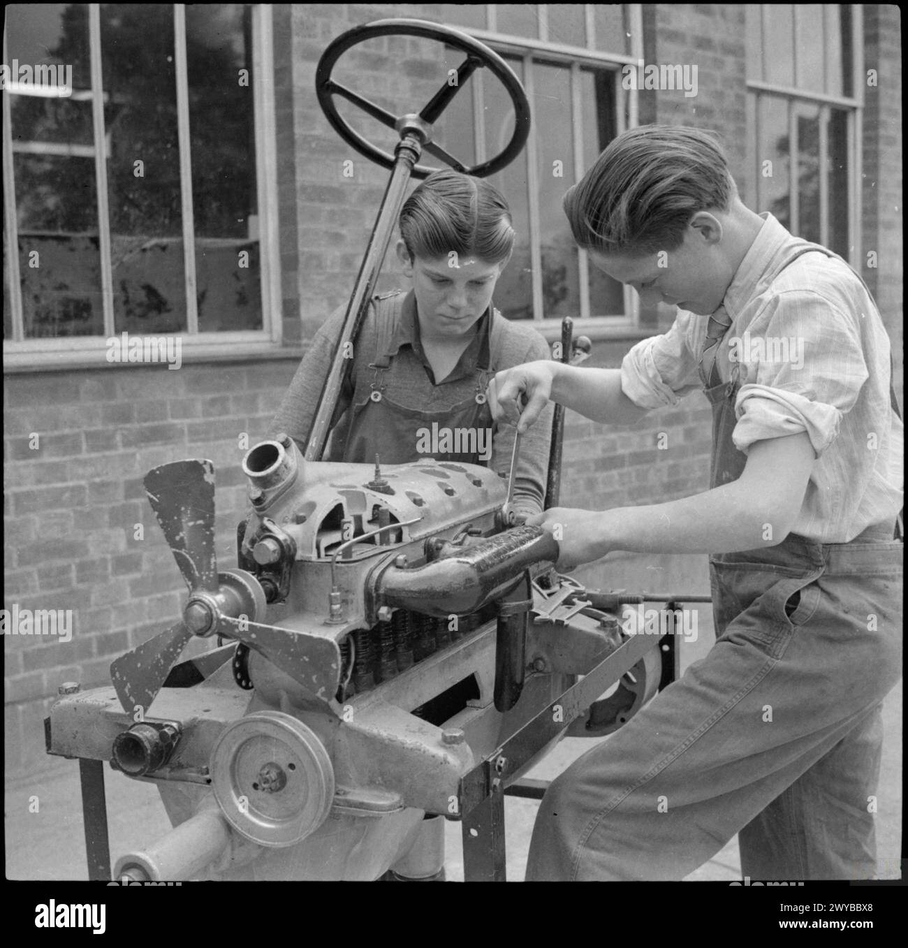 COUNTRY SCHOOL: ALLTAG AN DER BALDOCK COUNTY COUNCIL SCHOOL, BALDOCK, HERTFORDSHIRE, ENGLAND, GROSSBRITANNIEN 1944: an der Baldock County Council School untersuchen zwei Jungen einen Traktormotor. Die Schule hat einen Traktor Fahrclub, der zwei Hektar Land bewirtschaftet. , Stockfoto