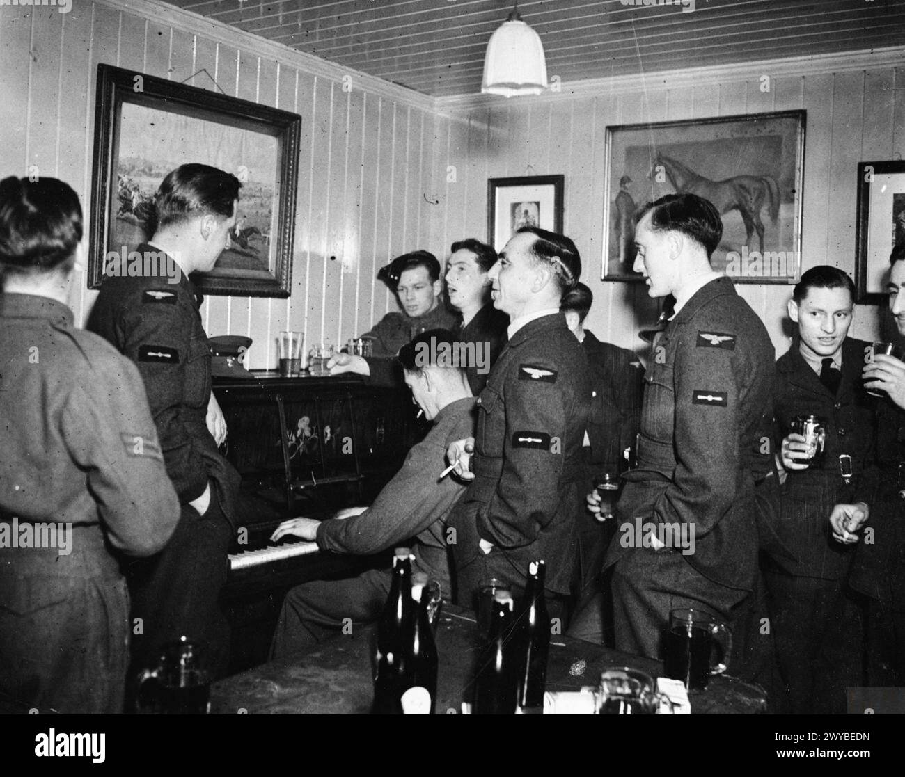 Flieger der No. 504 Squadron RAF treffen sich zwischen 1939 und 1945 in einem Pub in Middle Wallop, Hampshire, mit Getränken und Klavier. Stockfoto