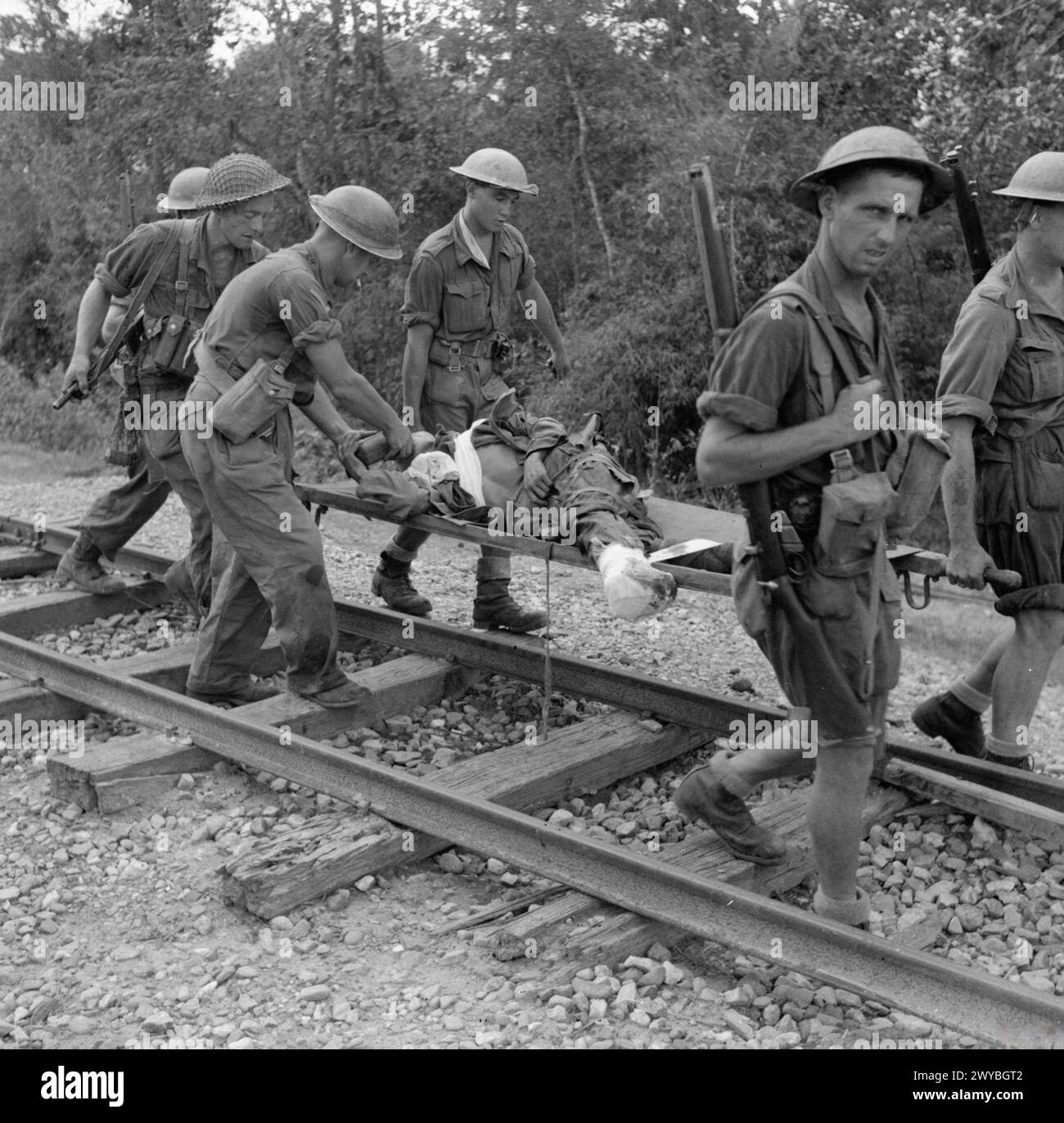 DIE BRITISCHE ARMEE IN BURMA 1944 – Ein verwundeter Gefangener wird während des Vormarsches auf Mawlu im November 1944 von Truppen der 36. Infanteriedivision auf einer Bahre entlang einer Eisenbahnstrecke getragen. , Stockfoto