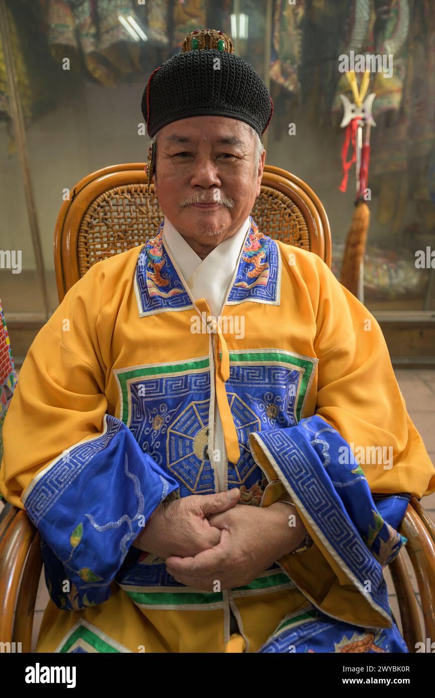 Porträt eines atraditionalen Priesters in traditioneller Kleidung mit zeremoniellen Insignien, die in die Kamera lächeln Stockfoto