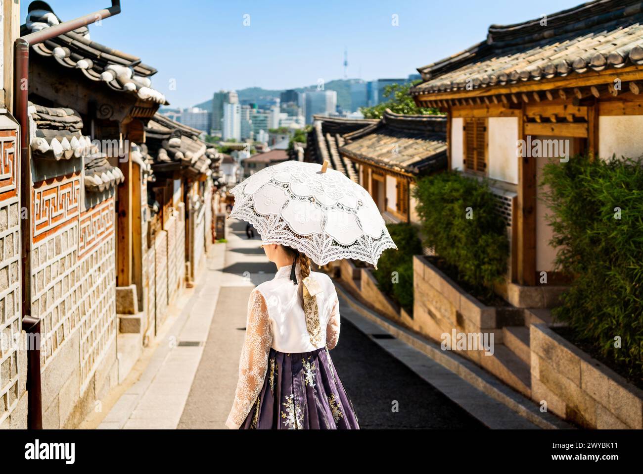 Südkorea, Seoul. Frau in Hanbok im Dorf Bukchon Hanok. Mädchen in traditionellem Kleid und Kostüm. Koreanische Tradition. Skyline der Stadt. Stockfoto