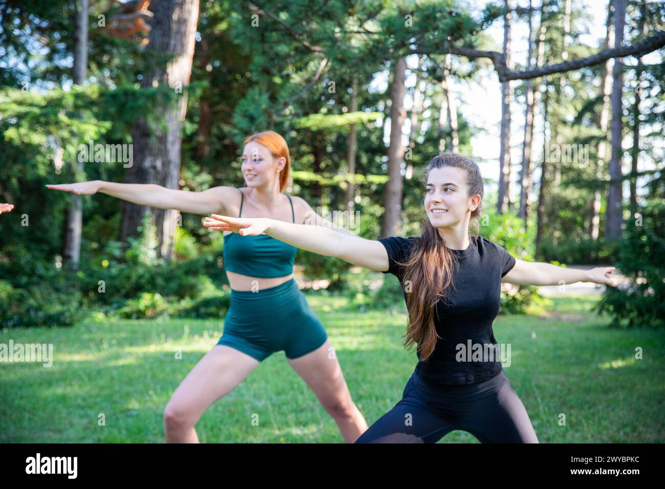 Zwei Frauen machen Yoga in einem Park während eines Sommertages, gesunde Lebensweise. Stockfoto