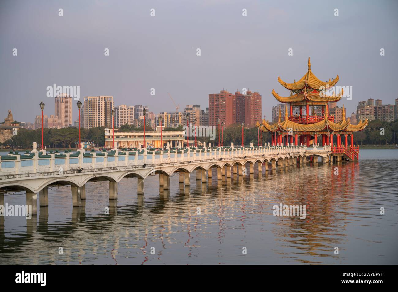 Ein ruhiger und malerischer Blick auf einen Pier, der sich über ruhiges Wasser in Richtung einer chinesischen Pagode unter blauem Himmel erstreckt Stockfoto