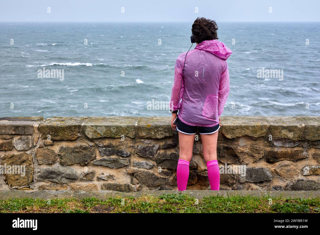 Frau, die Sport macht und auf das Meer blickt, Paseo Nuevo, Donostia, San Sebastian, Gipuzkoa, Baskenland, Spanien. Stockfoto